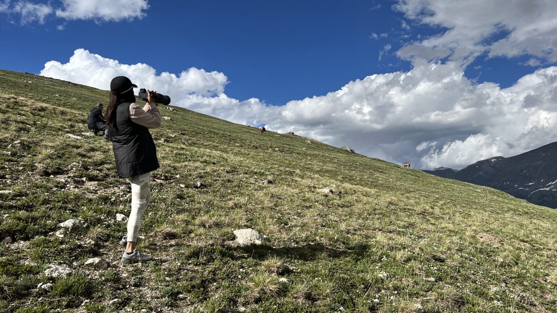 A person standing on top of a grass covered hill.